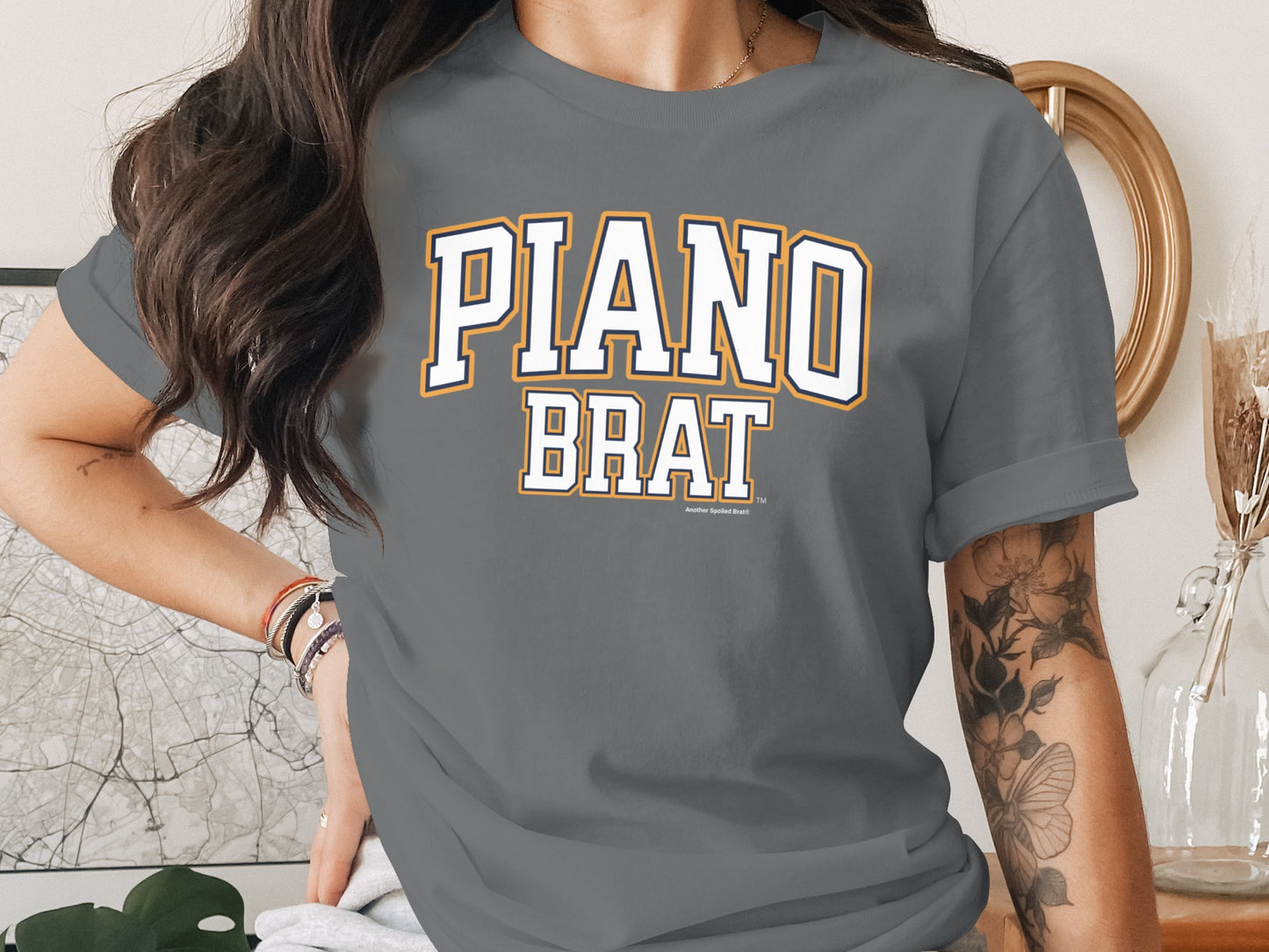 Gray t-shirt with white and orange "PIANO BRAT" text