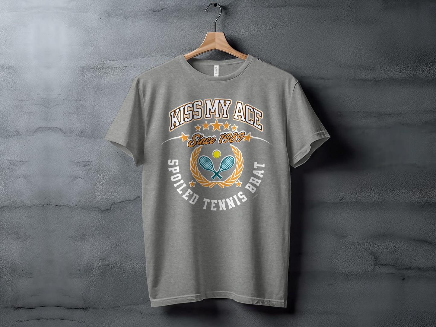 Grey t-shirt with "Kiss My Ace Since 1989 Spoiled Tennis Brat" text and tennis graphics.