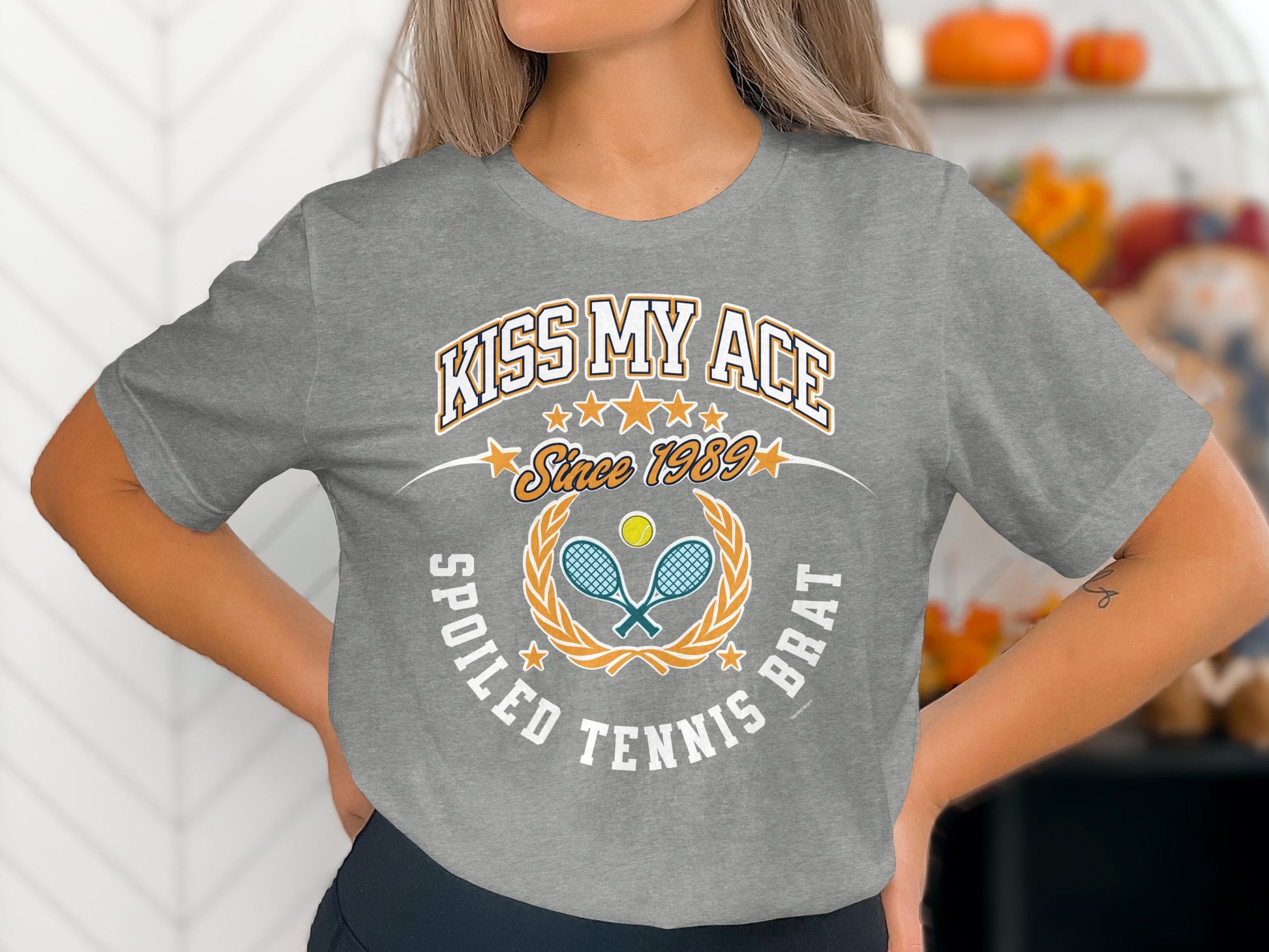 Grey t-shirt with "Kiss My Ace Spoiled Tennis Brat" text and tennis graphic.