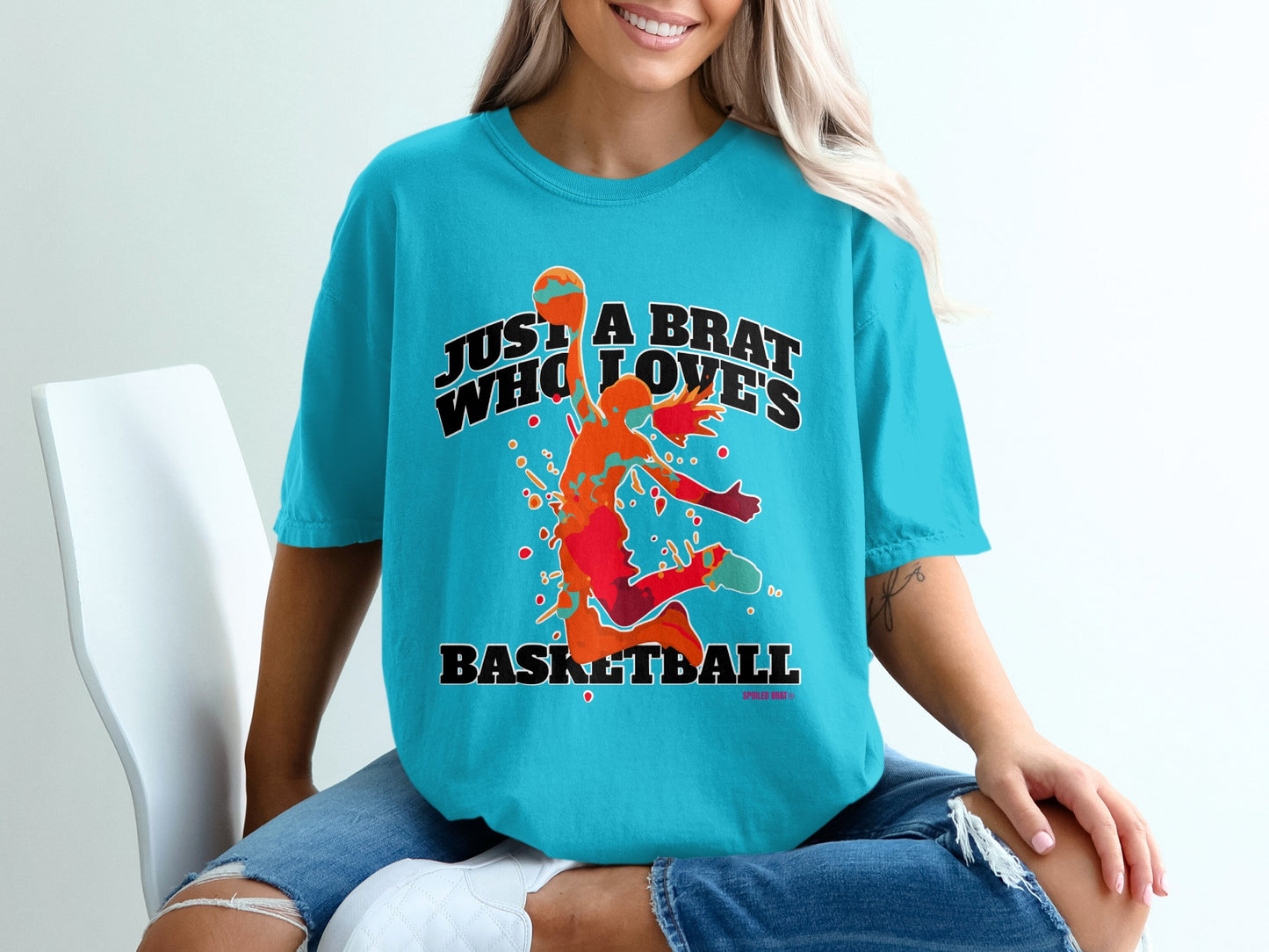 Turquoise t-shirt with "Just a Brat Who Loves Basketball" text and basketball player graphic.