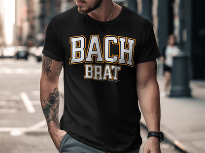 Black t-shirt with "BACH BRAT" printed in white and yellow collegiate lettering.