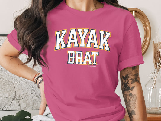 Pink t-shirt with "KAYAK BRAT" text in collegiate font, small text below.