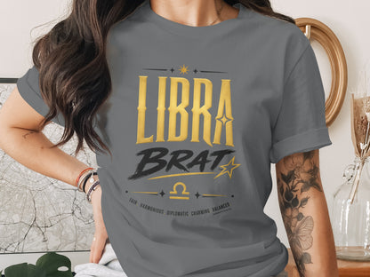 Grey t-shirt with "LIBRA BRAT" text, Libra symbol, and descriptive words.